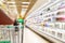 Woman hand hold supermarket shopping cart with abstract blur refrigerator shelves