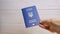 Woman Hand Holding a Blue Biometric Passport of Ukraine on White Background