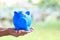 Woman hand holding blue piggy bank attached to the plaster on the head, Save money for Medical insurance and Health care concept
