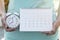 Woman hand holding calendar and alarm clock for planner, business, check for period schedule, healthy and travel plan