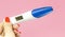 Woman hand holding digital pregnancy test isolated on pink. The pregnancy test screen with yes word.