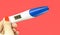 Woman hand holding digital pregnancy test isolated on red. The pregnancy test screen with yes word.