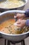 Woman hand holding dipper scooping freshwater snail in red curry Put in a plastic bag