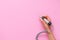 Woman hand holding electric nail manicure machine pen on pink background