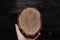 Woman hand holding empty circular piece of wood section texture on dark background. Copy space for text