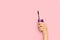 Woman hand holding an eyelash mascara on a pink background