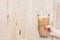 woman hand holding the glass iced coffee on wooden background