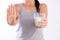 Woman hand holding glass of milk having bad stomach ache because of Lactose intolerance and another hand shows stop sign.