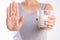 Woman hand holding glass of milk having bad stomach ache because of Lactose intolerance and another hand shows stop sign. health