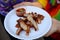 Woman hand holding Grilled pork marinated in herbs, cut into white paper plates With chili sauce