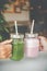 Woman hand holding healthy smoothie in eco friendly glass jar with paper straws in a luxury gym recreation area or vegan
