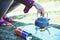 Woman hand is holding a kettle. Placed on a picnic gas stove