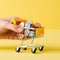 Woman hand holding mini shopping cart with coins on yellow background. Online shopping concept. Ai generative