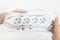 Woman hand holding new four outlets power extension cord in a transparent plastic pakage over white table. Electric power strip