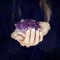 Woman hand holding purple crystal, amethyst, melancolic sensual studio shot