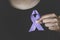 Woman Hand Holding Purple Ribbon, Domestic Violence Awareness Month October concept with deep purple awareness ribbon