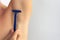 Woman hand holding razor to shave hairy unshaved armpit holding arm straight on the white background