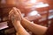 Woman hand holding rosary against cross and praying to God at church