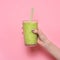 Woman hand holding smoothie shake against pink wall.