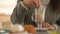 Woman hand holding spoon and stirring coffee latte at table with sweet cake