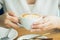 Woman hand holding a white coffee mug. Coffee is a latte. table on the wooden table in vintage style, taken from the top view,