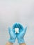 Woman hand holding white tooth on pastel blue background. Dentist stomatology medical concept
