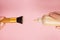 Woman hand holds a bottle of foundation, puts on a brush, on a pink background. Makeup artist work concept, copy space