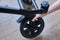 A woman hand holds a broken wheel of a baby carriage. Damage and repair of the wheels of the metal frame of the stroller