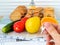 Woman hand holds the key of cell with cookies. Cookies are in the cage locked with padlock. Vegetables, fruits and measuring tape