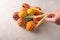 Woman hand holds mixed organic fruit, vegetables and greens in a string bag on light background. Zero waste add ecology