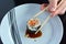 Woman hand holds one Makizushi sushi fresh maki roll with chopsticks