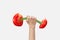Woman hand holds sport barbell made from natural cut tomatoes.