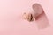 Woman hand holds toilet paper from a hole in a pink background. Concept, copy space