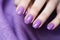 Woman hand with lavender color nail polish on her fingernails. Purple nail manicure with gel polish at luxury beauty salon. Nail