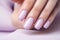 Woman hand with lavender color nail polish on her fingernails. Purple nail manicure with gel polish at luxury beauty salon. Nail