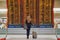 Woman with hand luggage in international airport terminal, looking at information board