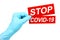 Woman hand in medical gloves holds red sign Stop Covid-19