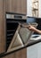 Woman hand opening metallic door on built-in oven