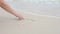 Woman hand paint heart symbol on beach sand. Pensacola Beach, Florida.