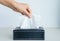 Woman hand picking white tissue paper from tissue box.