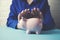 Woman hand piggy bank on wooden table