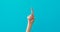 Woman hand points down by elegant finger on turquoise
