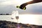 Woman hand pouring champagne into glasses on golden beach of azure calm Spanish seashore with waves in summer sunset or sunrise