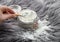 Woman hand pouring corn starch cornflour powder on long hair fur carpet for cleaning and stain removal.