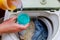 Woman hand pouring washing powder into the washing machine