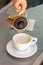 Woman hand pours black tea from glass teapot into ceramic cup