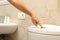 Woman hand presses the toilet flush button