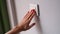 Woman hand presses white light switch closeup