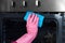 woman hand in protective glove with rag cleaning oven at home kitchen