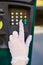 Woman hand in protective single use glove presses parking meter button on a street of Paris, France